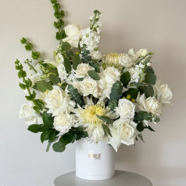 White floral arrangement in a white hatbox-style container