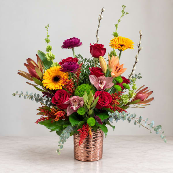 Mixed bouquet in a copper vase with roses, gerberas, and orchids