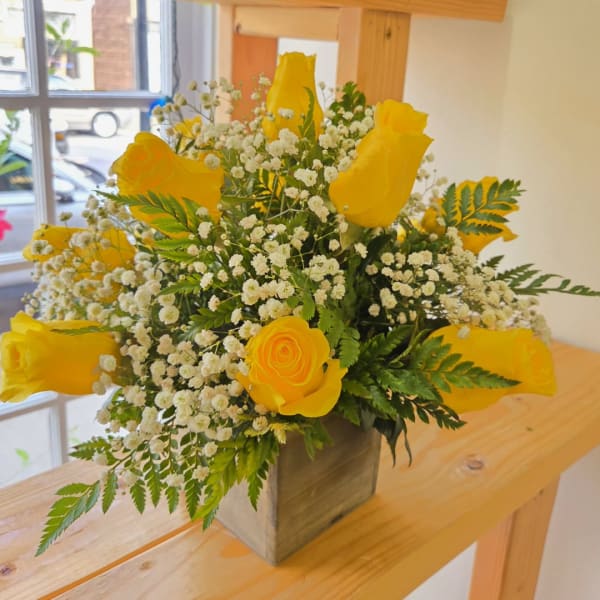 Yellow roses and baby's breath in a square vase
