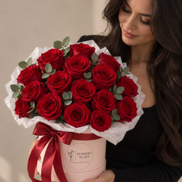 Woman holding a box of red roses with white wrapping and a red ribbon