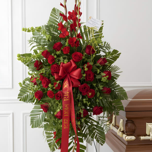 Tall red rose and gladiolus funeral spray with a red ribbon
