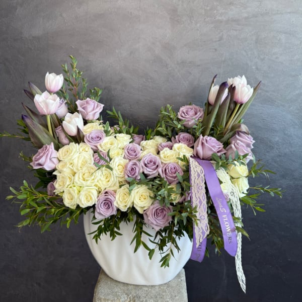 Lavender and cream roses with pale tulips in a white vase