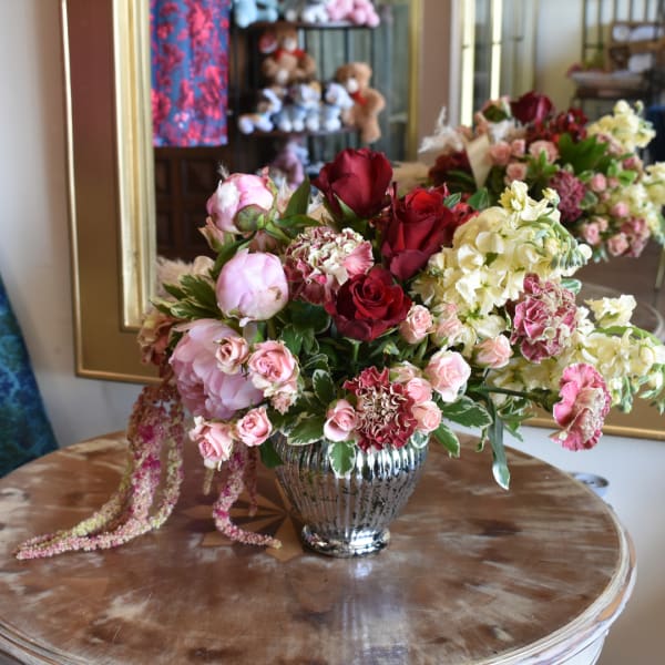 Mixed bouquet of roses, peonies, and carnations in a silver vase