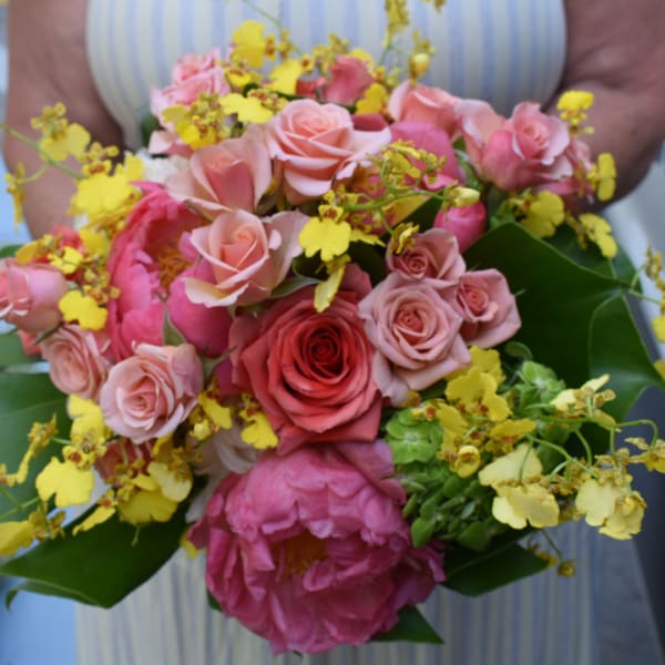 Handheld bouquet of pink and yellow flowers with roses and peonies