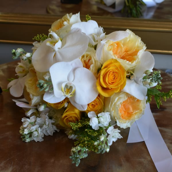 Bouquet of white orchids and yellow roses with a white ribbon