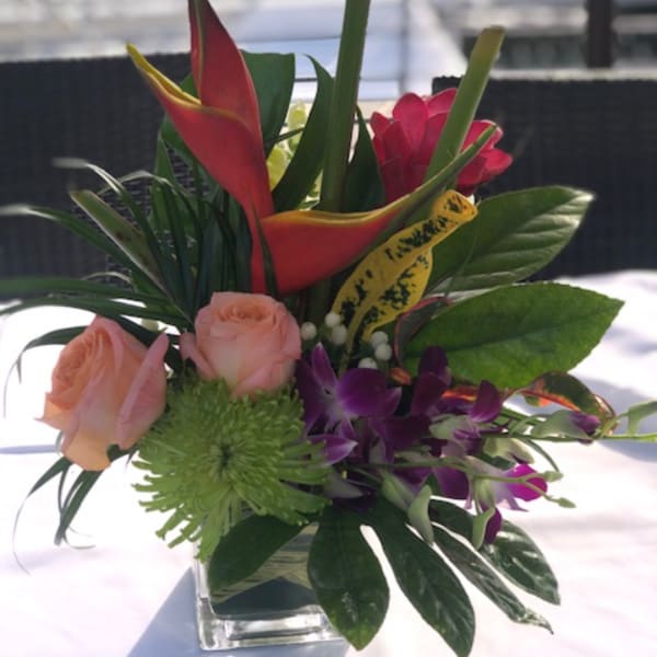 Tropical flower arrangement with roses, orchids, and calla lilies in a glass vase