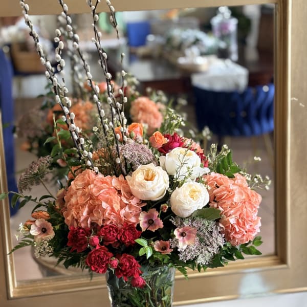 Mixed bouquet in a clear glass vase with peach, white, and red blooms