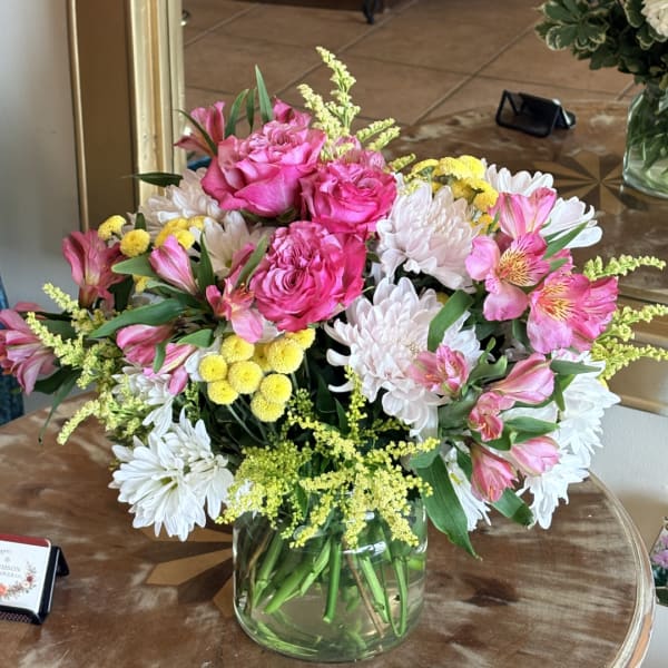 Pink roses and white daisies arranged in a clear glass vase