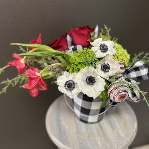 Bouquet of red roses and white anemones in a black-and-white checkered container