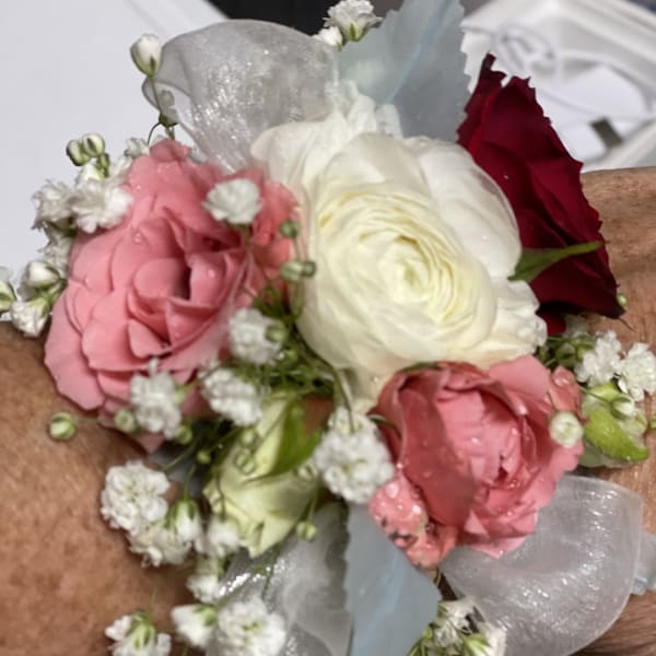 Small wrist corsage with pink, white, and red flowers and sheer ribbon