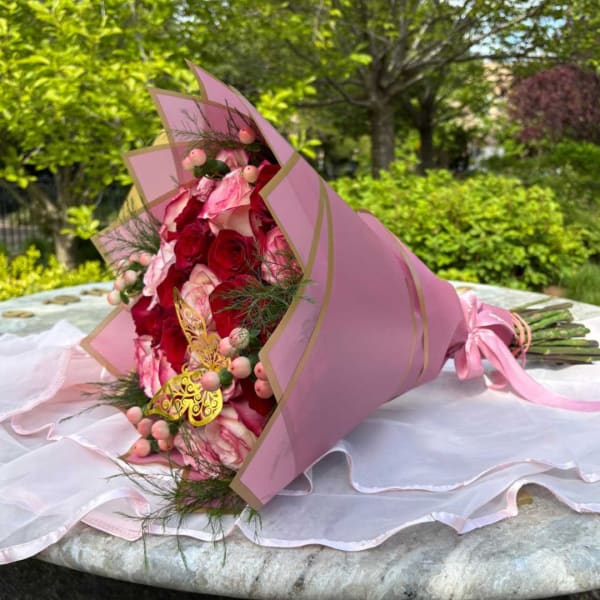 Pink and red rose bouquet wrapped in pink paper with ribbon