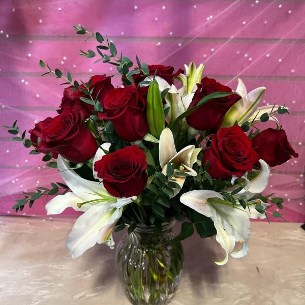 Red roses and white lilies arranged in a glass vase