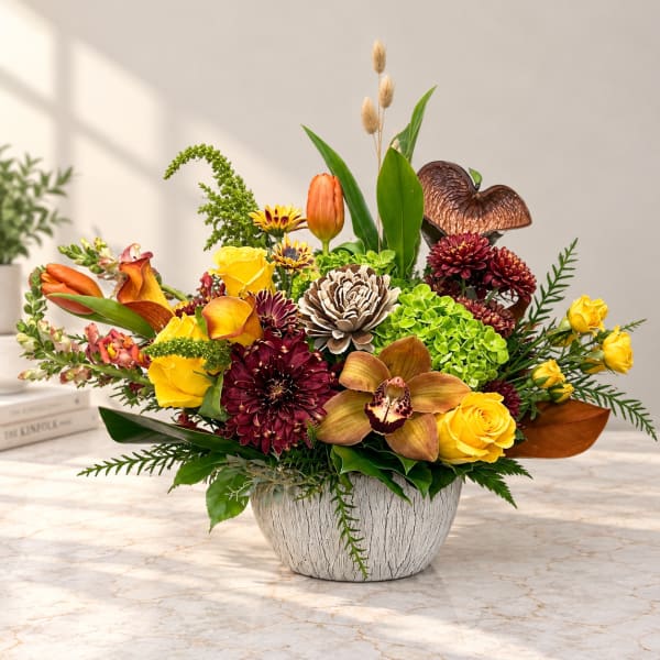 Mixed floral arrangement in a white textured bowl with yellow roses and orange blooms
