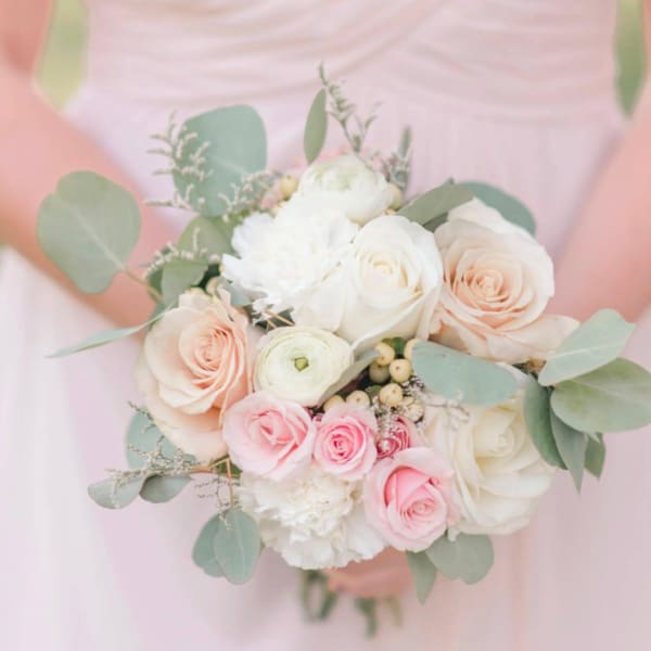 Pastel bridal bouquet of roses, ranunculus, and white blooms with eucalyptus