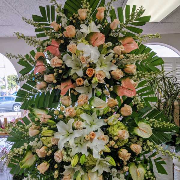 Large standing floral spray with white lilies, peach roses, and anthuriums