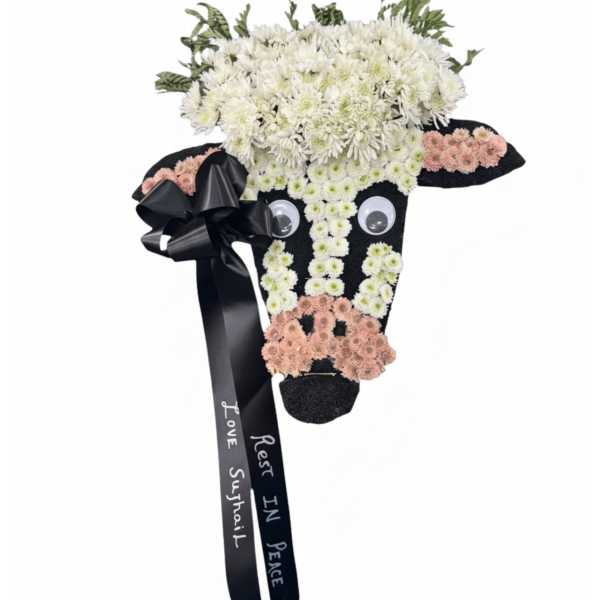 Cow-shaped floral tribute with white and pink flowers and a black ribbon