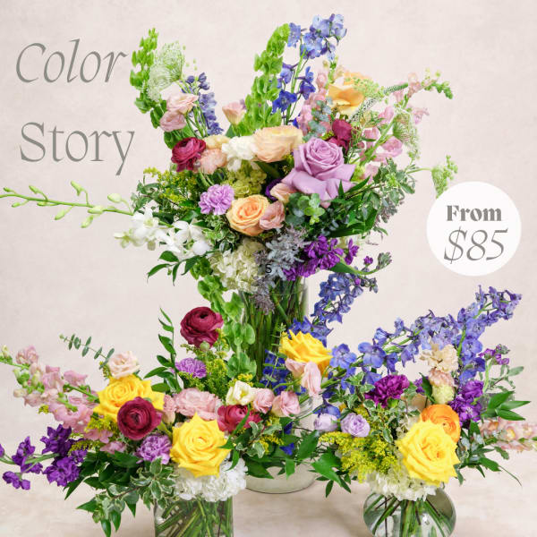 Colorful mixed flower arrangements with roses, delphinium, and orchids in glass vases