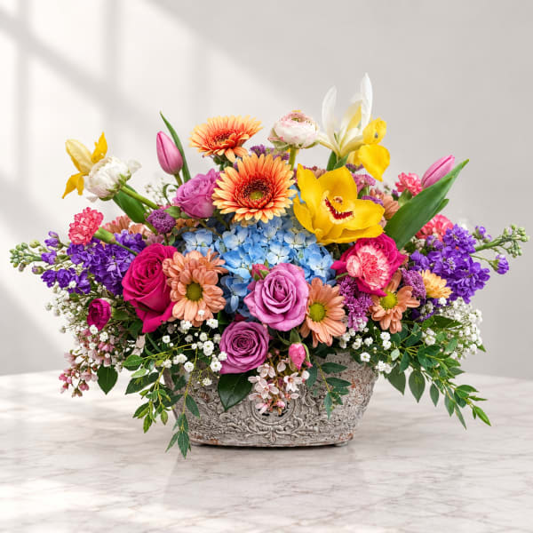 Colorful mixed flower arrangement in an ornate rectangular vase