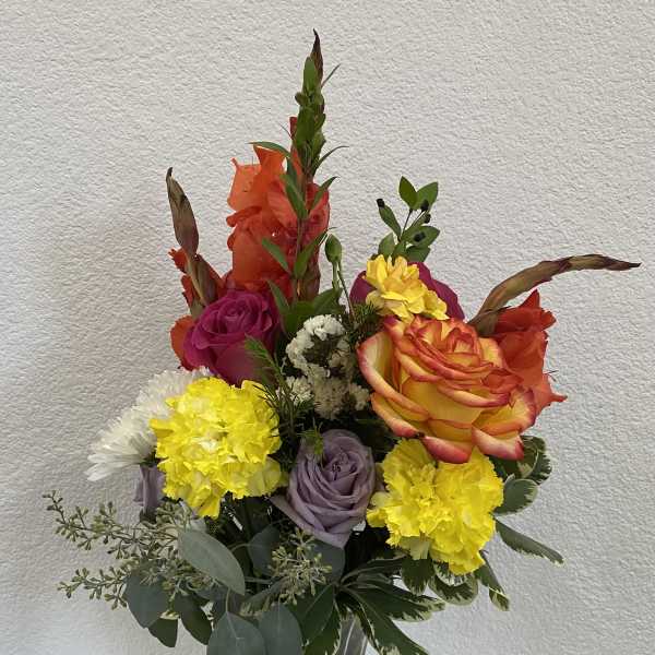 Mixed bouquet in a clear glass vase with roses, carnations, and daisies
