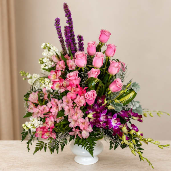 Pink roses and orchids arranged in a white vase