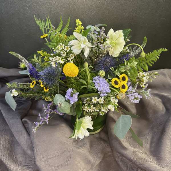 Mixed bouquet with white lilies, yellow blooms, and purple flowers in a vase
