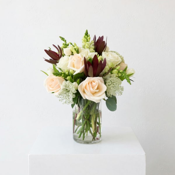 Bouquet of cream roses and white flowers in a clear glass vase