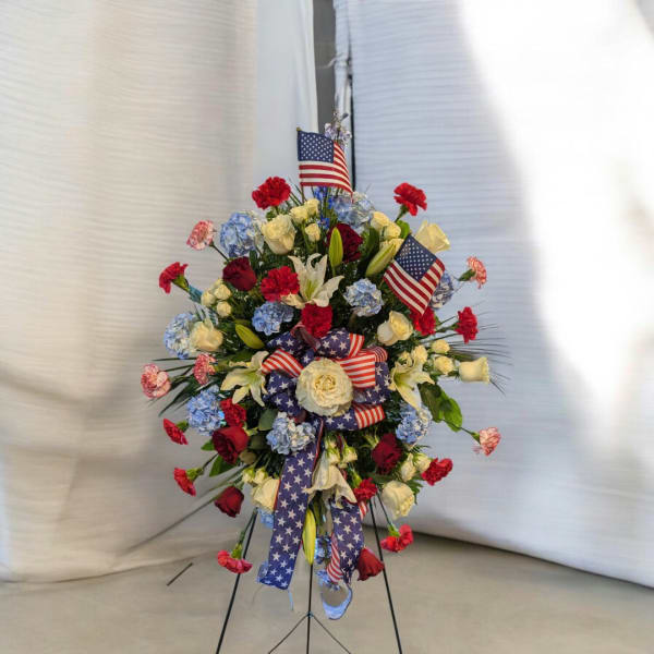 Standing floral spray with red, white, and blue flowers and American flags