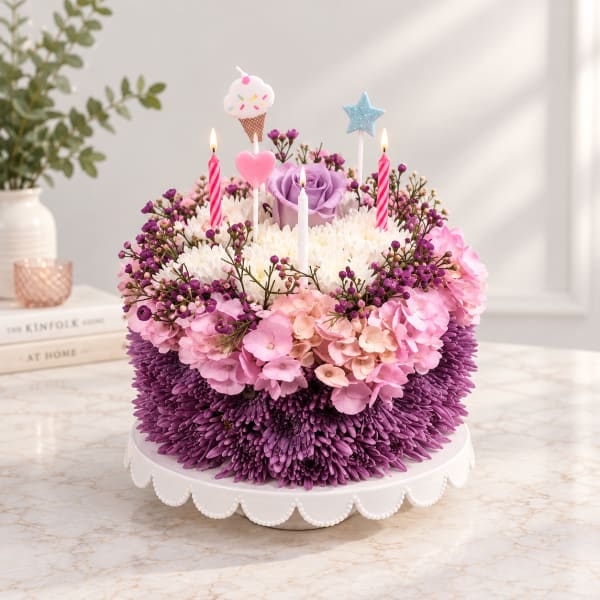 Round floral cake with purple and pink flowers and birthday candles