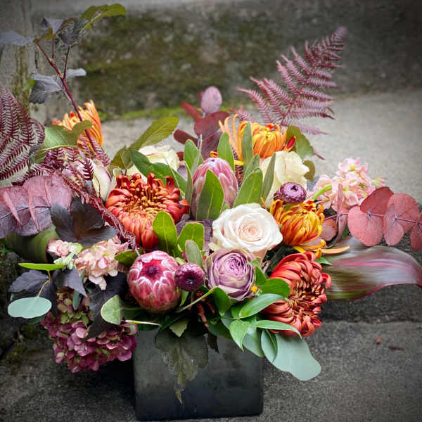 Mixed bouquet in a black vase with orange, pink, and white blooms