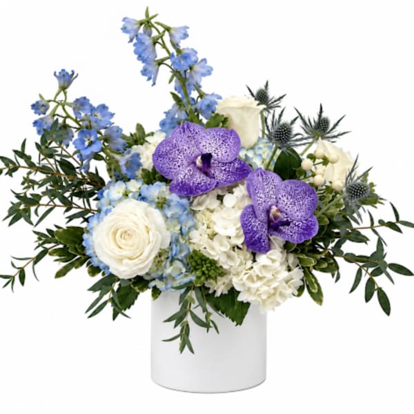 White and blue floral arrangement with purple orchids in a white vase