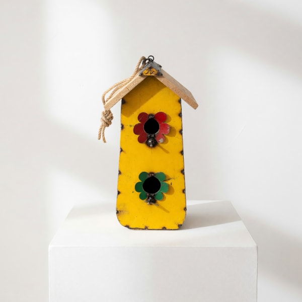 Yellow wooden birdhouse with red and green flower decorations