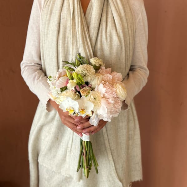 Person holding a pale blush and white bridal bouquet
