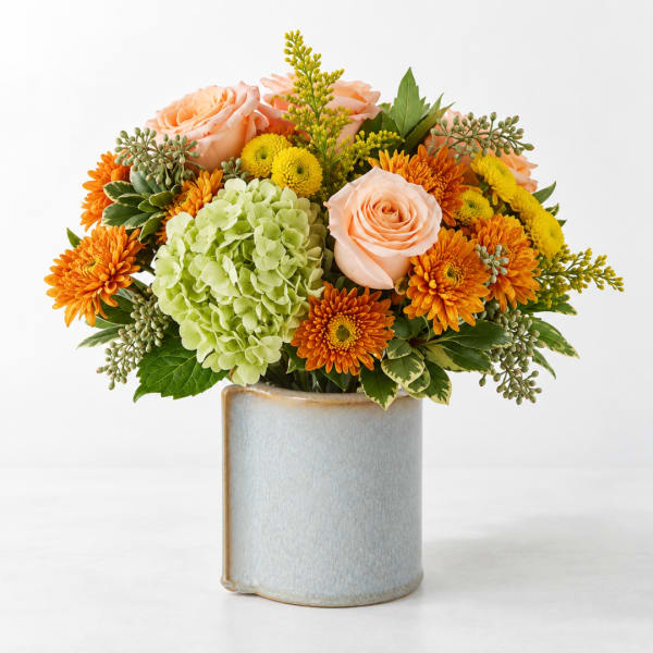 Peach roses and orange mums in a ceramic vase