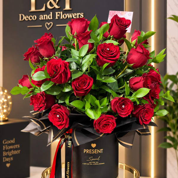 Red roses arranged in a black gift box with ribbon