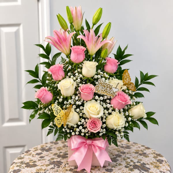 Pink lilies and roses in a box with a birthday topper