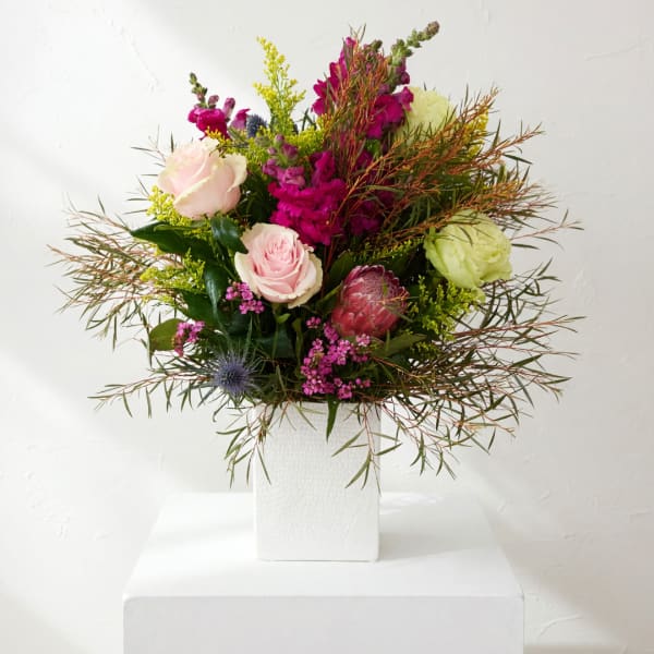 Mixed bouquet of pink and green flowers in a white vase