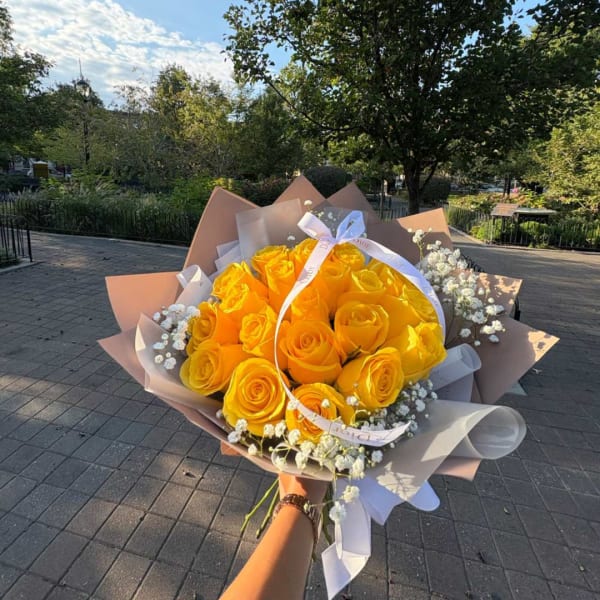 Handheld bouquet of yellow roses with white baby's breath