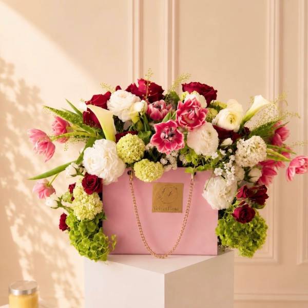 Pink gift box overflowing with red, white, and pink flowers