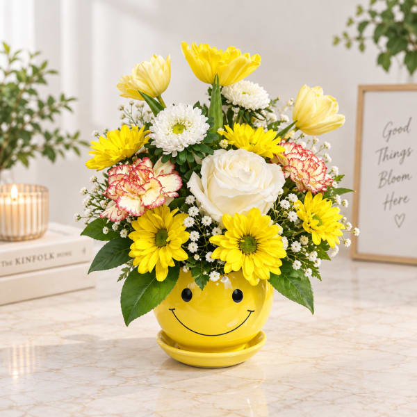 Yellow and white flower arrangement in a smiley-face pot