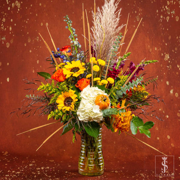 Mixed bouquet in a clear glass vase with sunflowers, roses, and white hydrangea