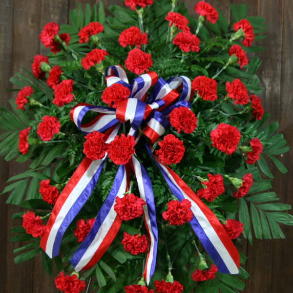 Red carnation standing spray with a red, white, and blue ribbon bow
