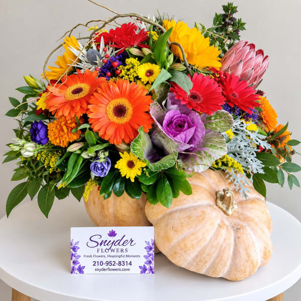 Colorful flower arrangement in a pumpkin-shaped container with a business card in front