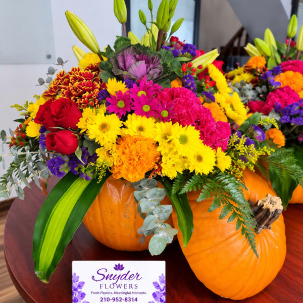Colorful mixed flower arrangement in pumpkins with a business card in front