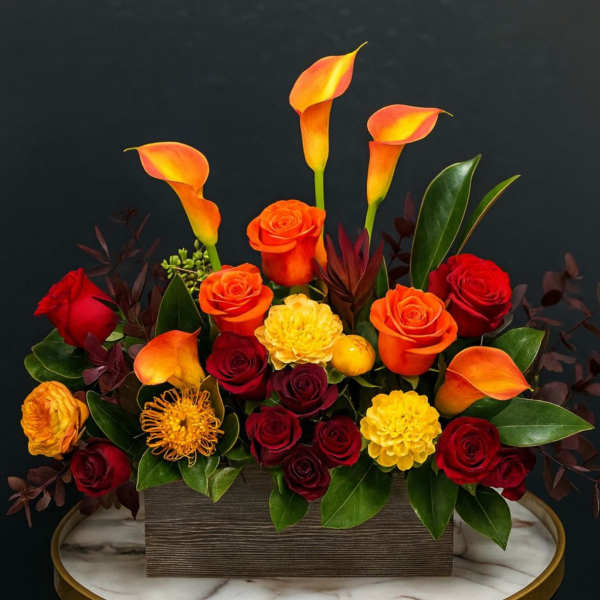 Orange calla lilies and red roses arranged in a rectangular box