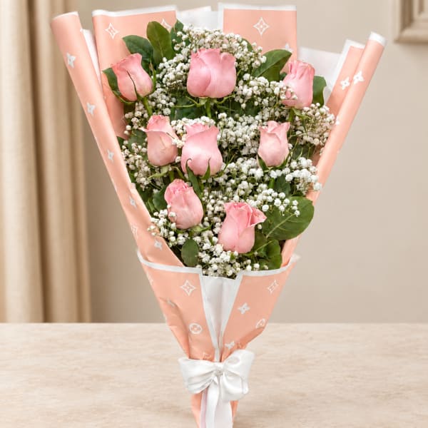 Pink rose bouquet wrapped in peach paper with a white bow