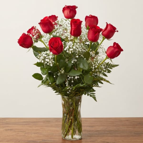 Red roses arranged in a clear glass vase with white baby's breath