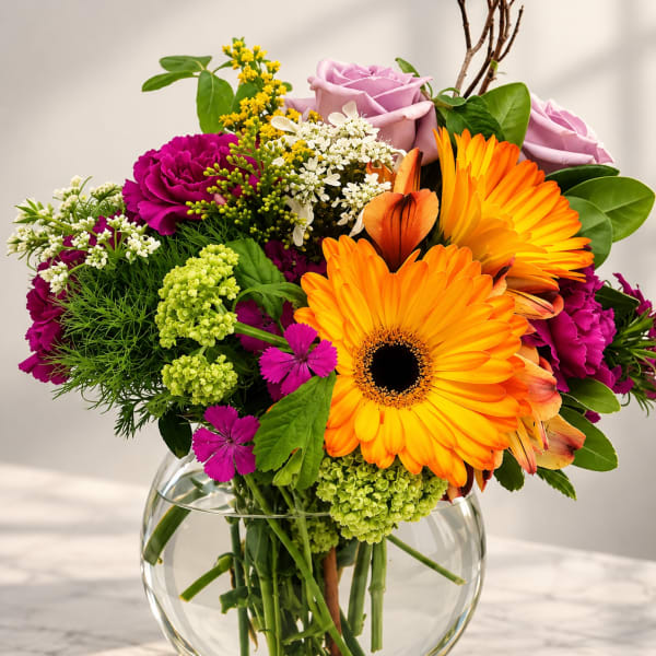 Mixed bouquet with orange gerbera daisies and pink roses in a glass vase