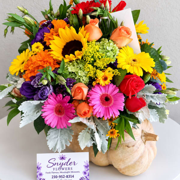 Colorful mixed bouquet in a pumpkin-shaped vase with roses and daisies