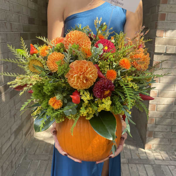 Orange and red floral arrangement in a pumpkin container