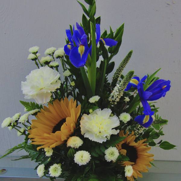 Bouquet with blue irises, sunflowers, and white carnations in a painted vase